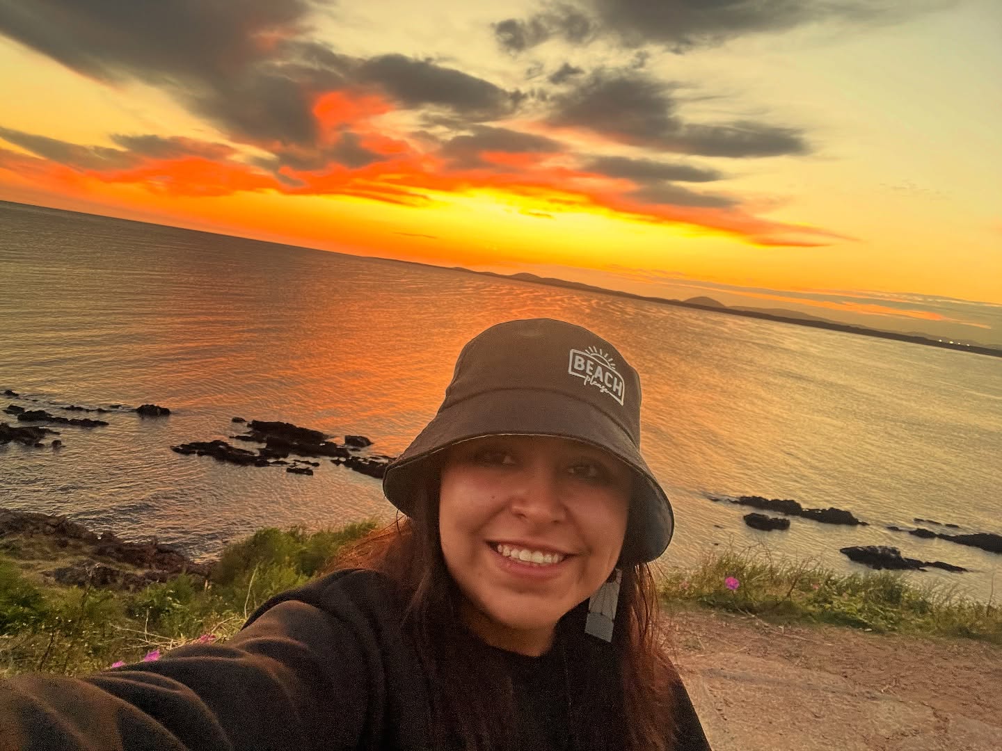 Vanessa sonriendo frente al mar durante un atardecer naranja